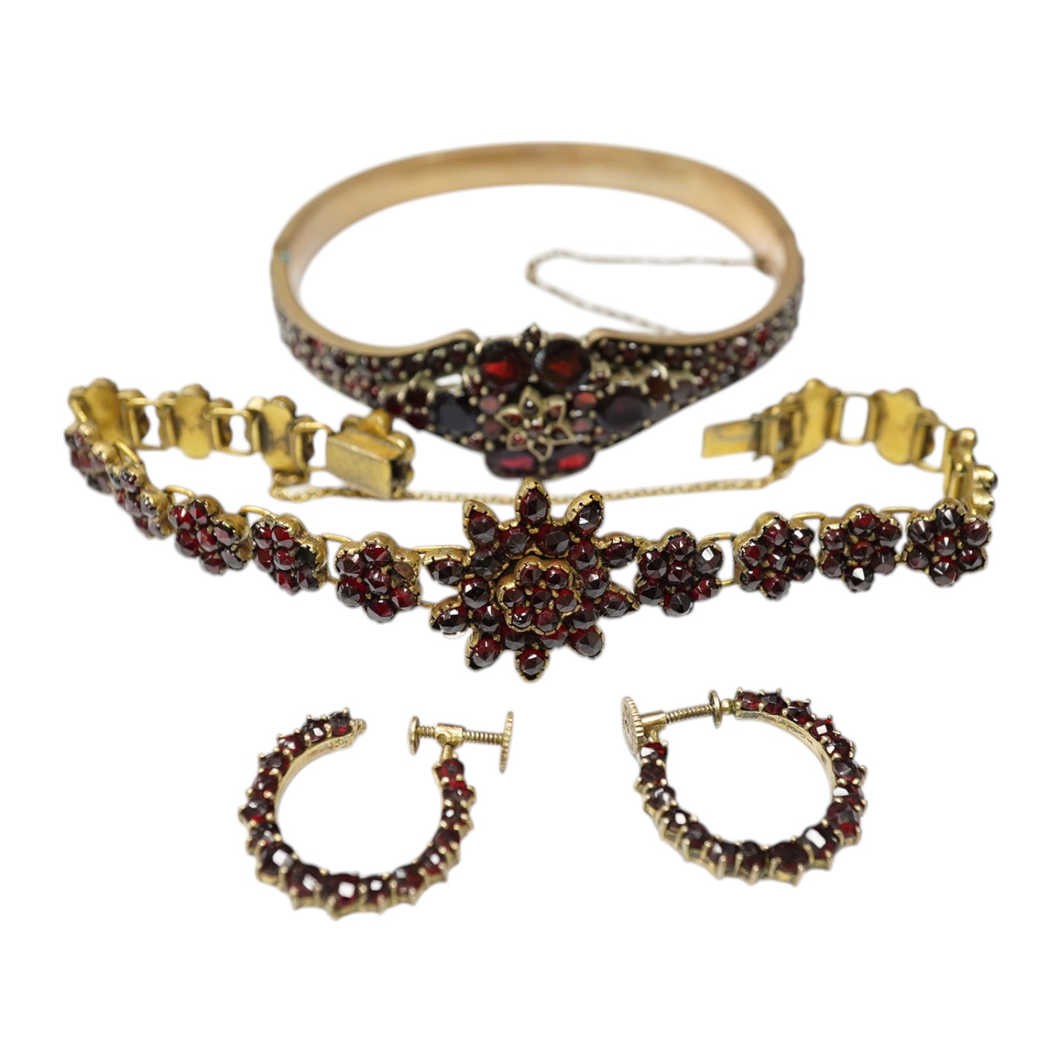 Three items of gilt white metal and garnet paste cluster set jewellery, comprising a bracelet, bangle and pair of Czechoslovakian earrings. Condition - fair